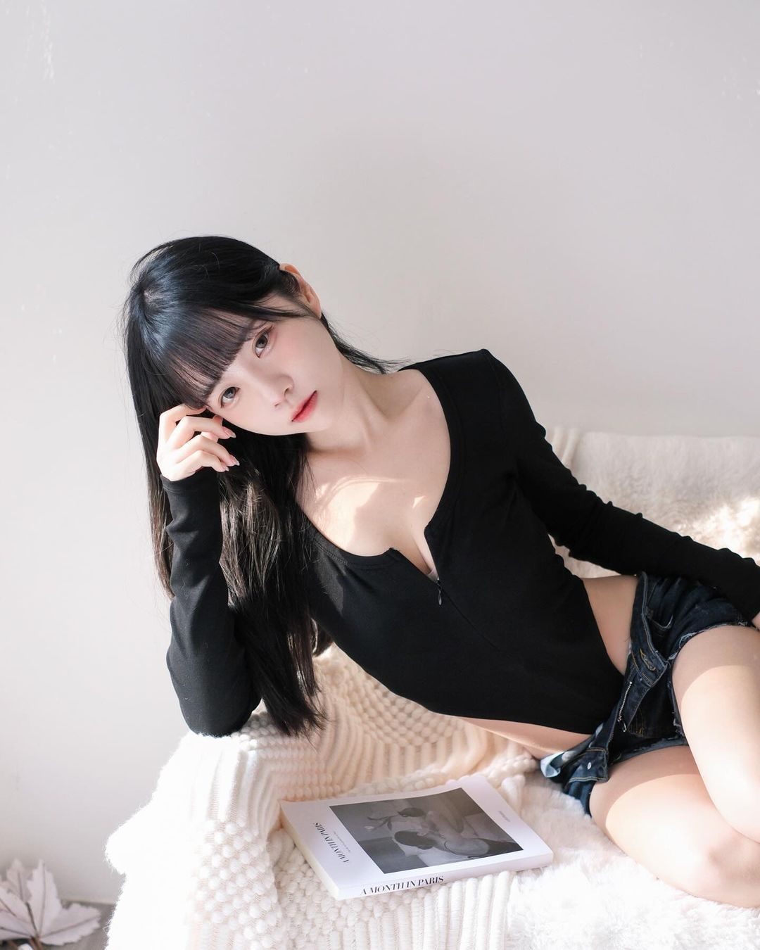 Cute petite Taiwanese girl lying on a sofa wearing shorts and a seductive outfit.